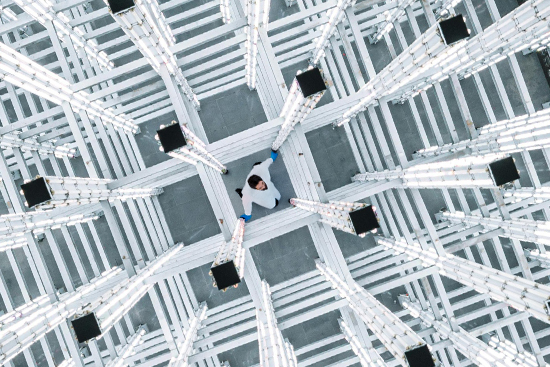 A scientist in a lab coat trapped in a grid of impossibly large scaffolding