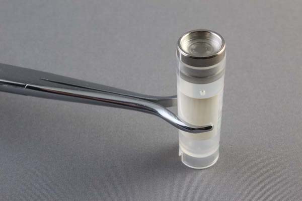 Vial forceps holding onto a glass vial