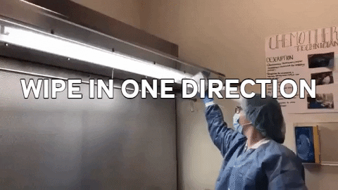 An animated gif of a lab tech wiping down the hood of an Isolator with text reading WIPE IN ONE DIRECTION
