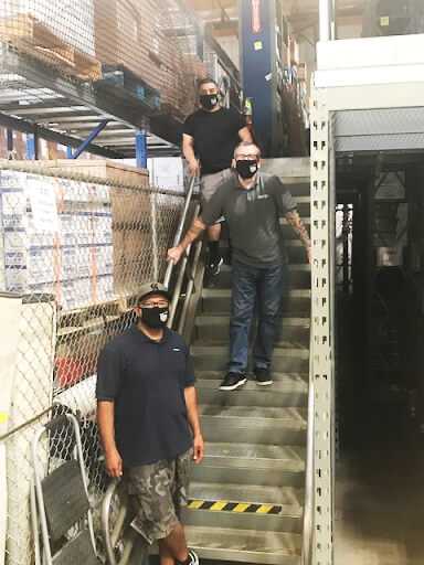 3 member volunteers on a warehouse staircase wearing PDA facemasks