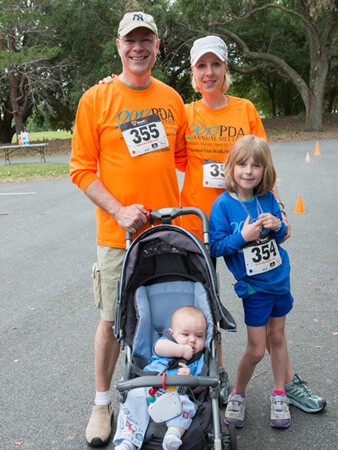 Maik Jornitz with his wife and two daughters, one in a stroller, attending and dressed for a fun run event